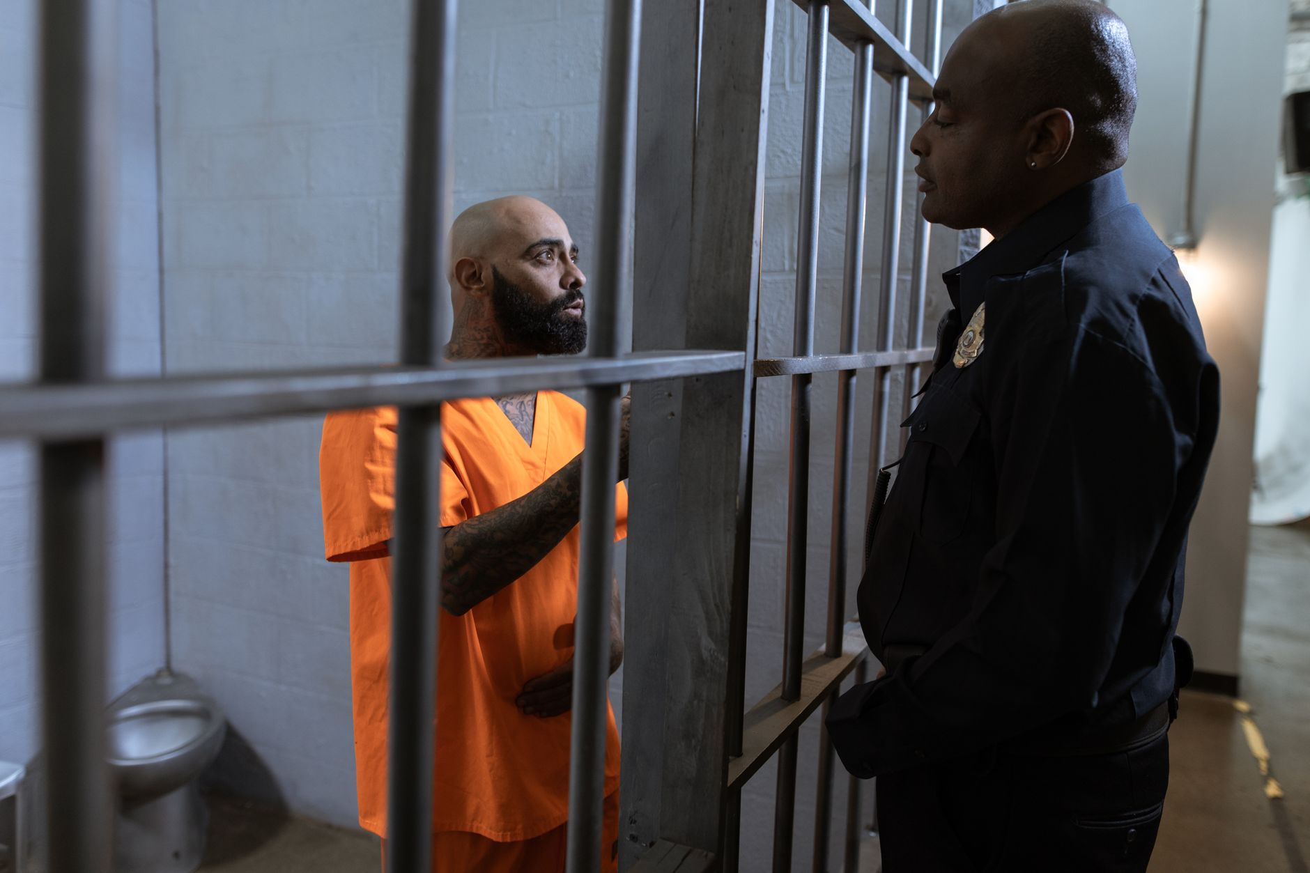 A prison guard talks with an inmate inside a cell.