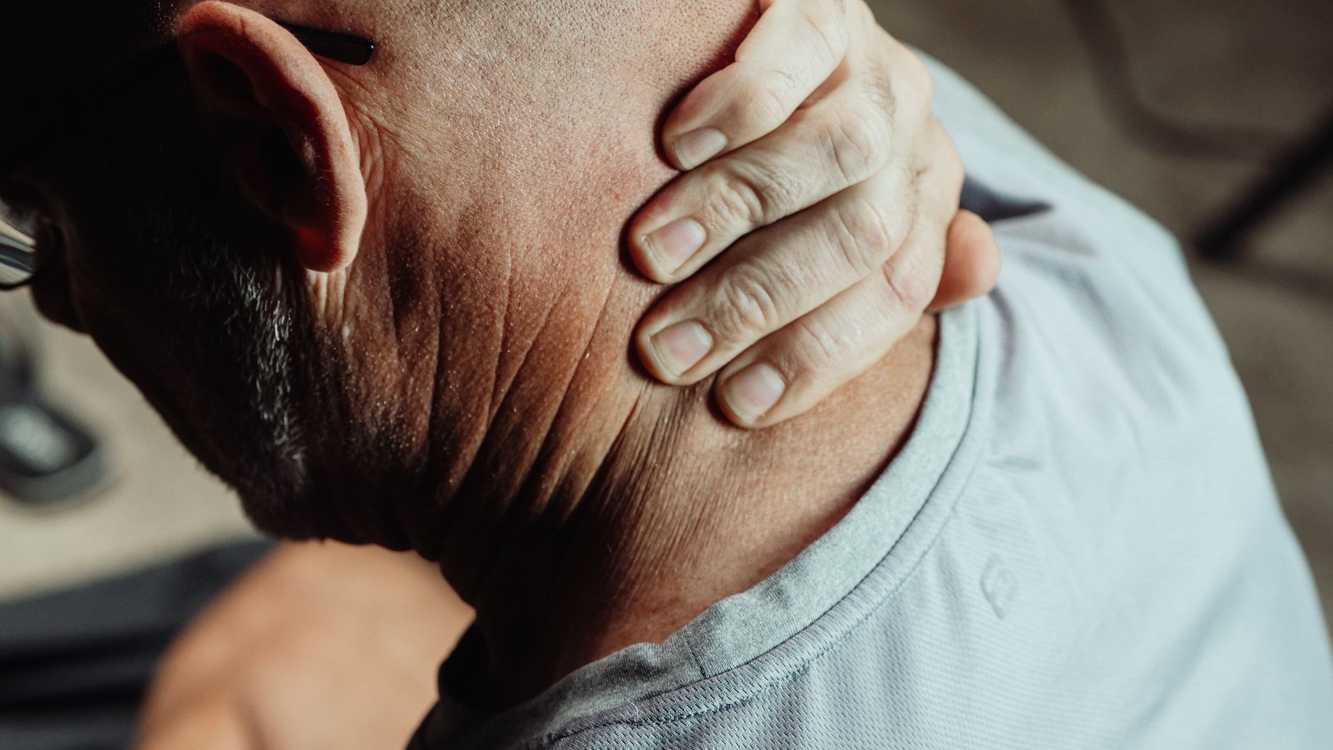 Man holding the back of his neck in discomfort from pain or tension.