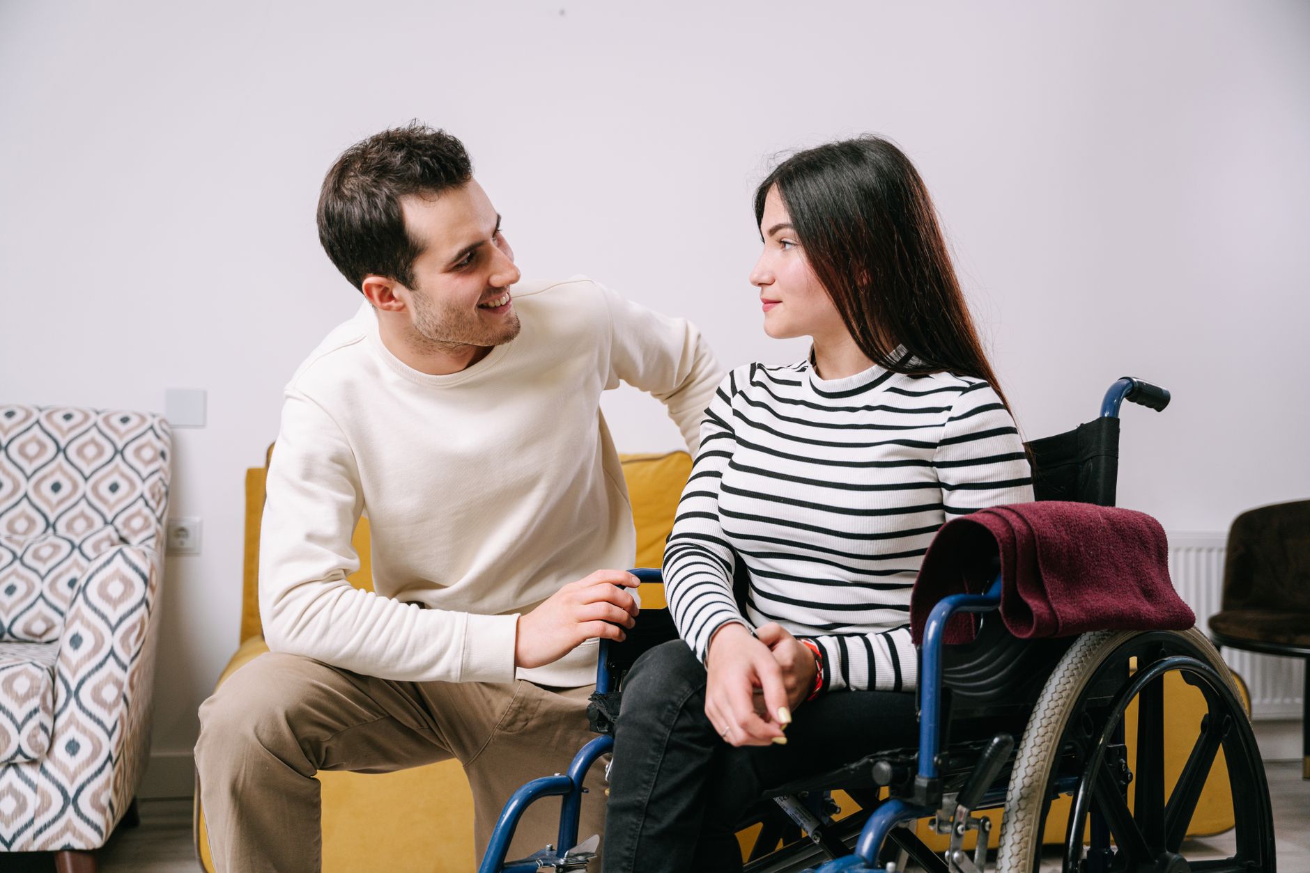 Man in a wheelchair embracing his partner, sharing a tender moment of support and connection.