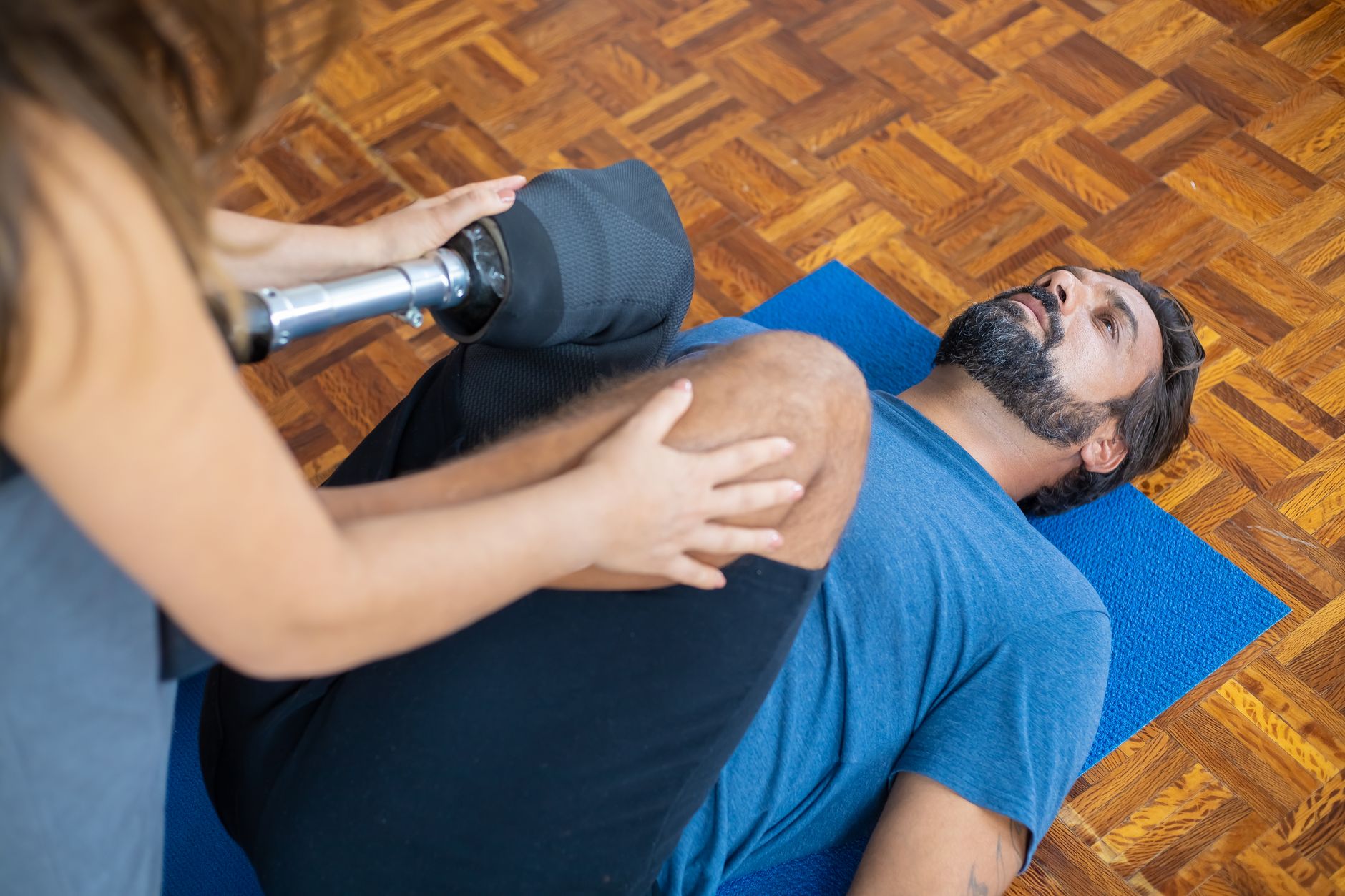 a young adult in a wheelchair in a spinal-cord-injury rehabilitation gym with a physical therapist