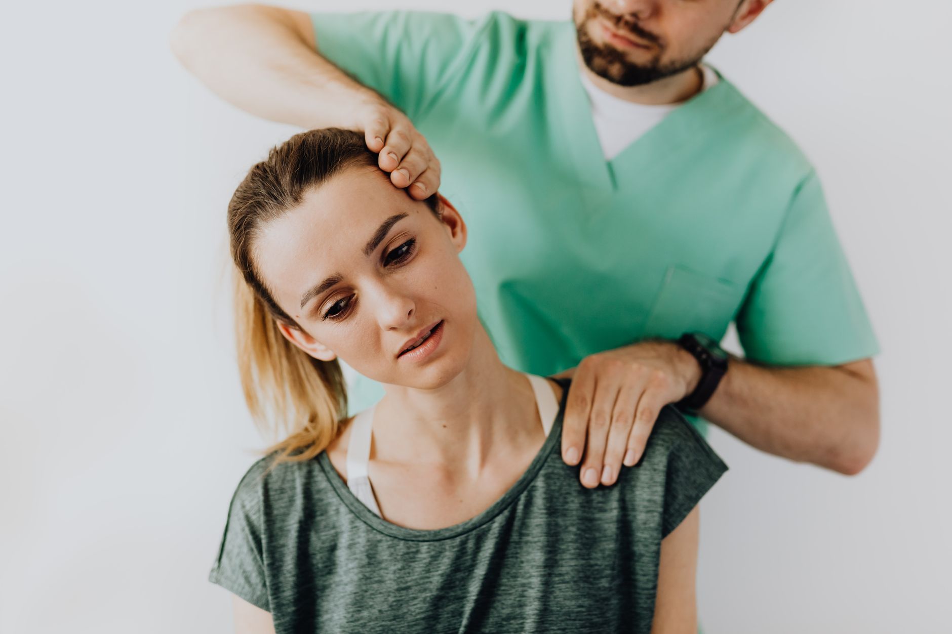 Massage therapist gently stretches and massages a female patient's neck and shoulders during therapy.