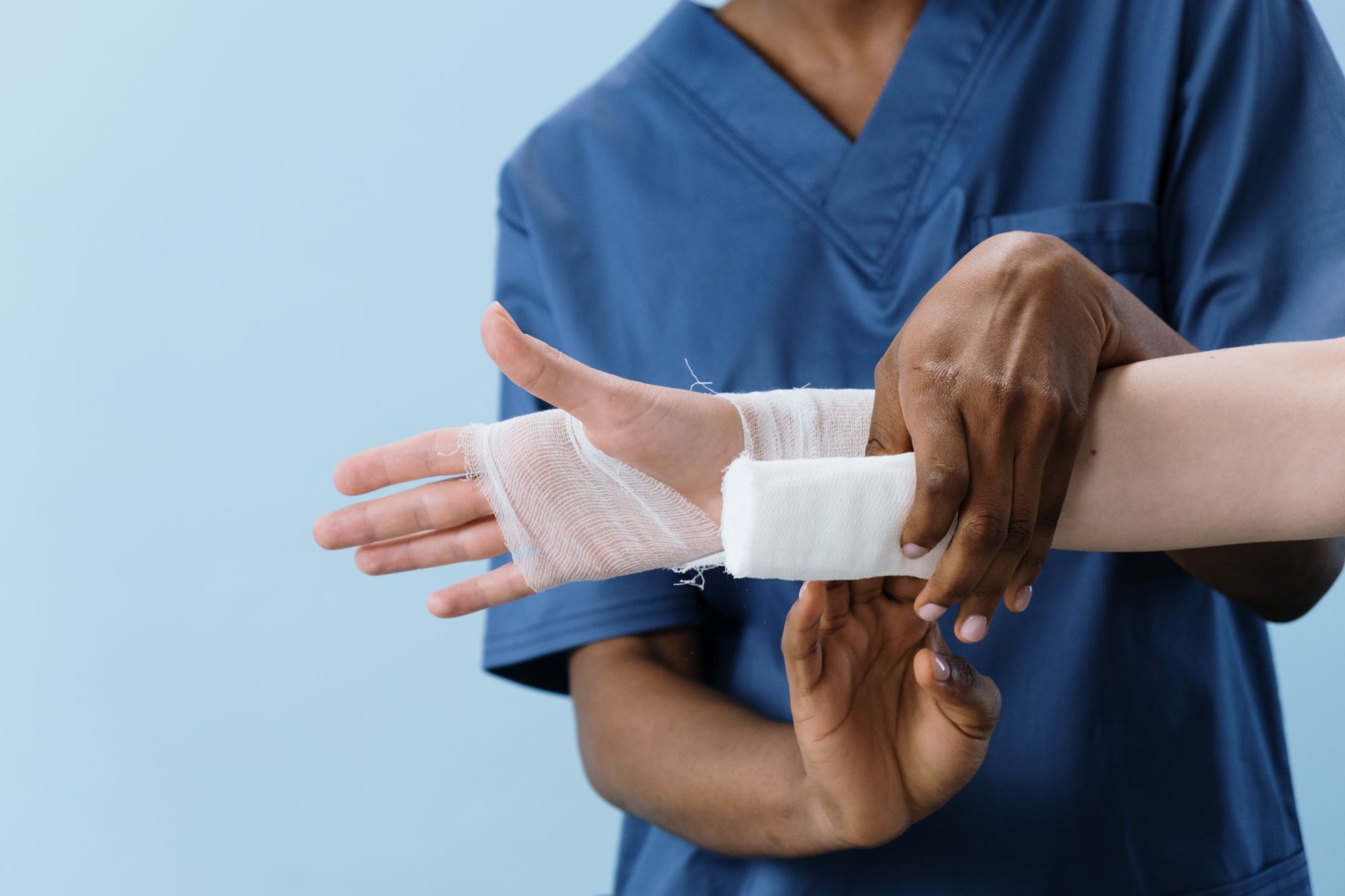 Medical professional wrapping a bandage around an injured person's hand.