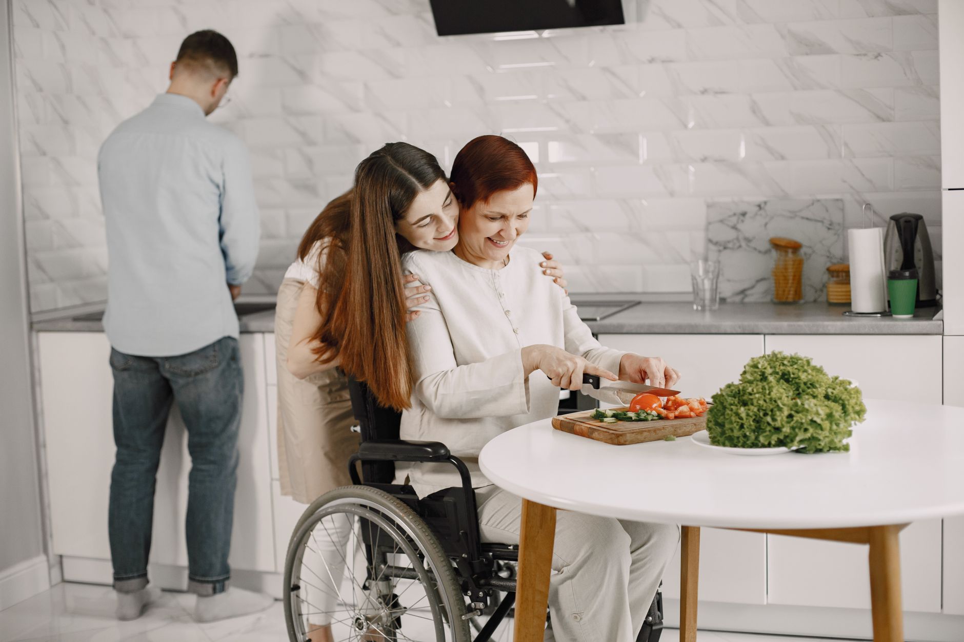 Mujer en silla de ruedas cocinando con su familia en una cocina luminosa.