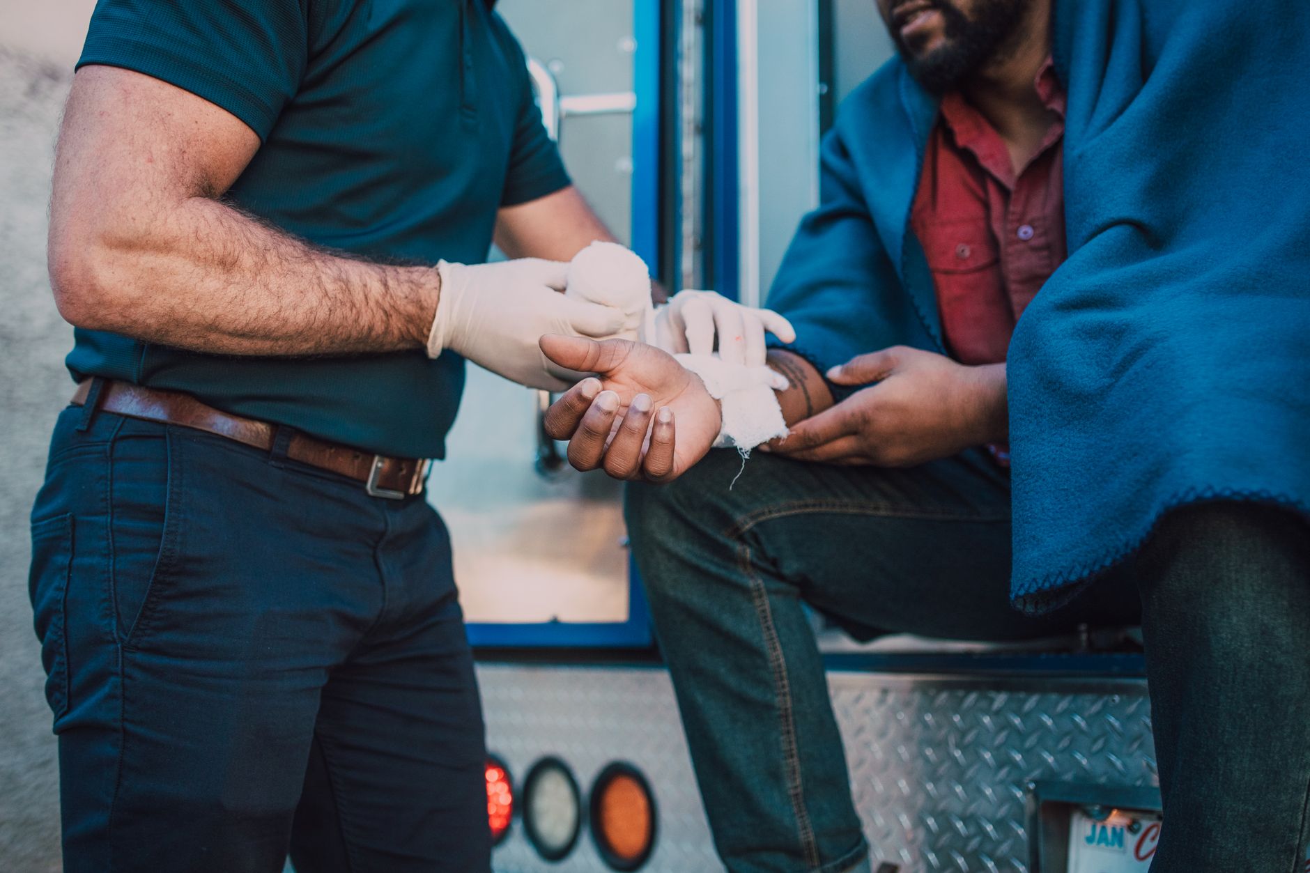 Paramedic provides first aid to an injured person beside an ambulance at an accident scene.