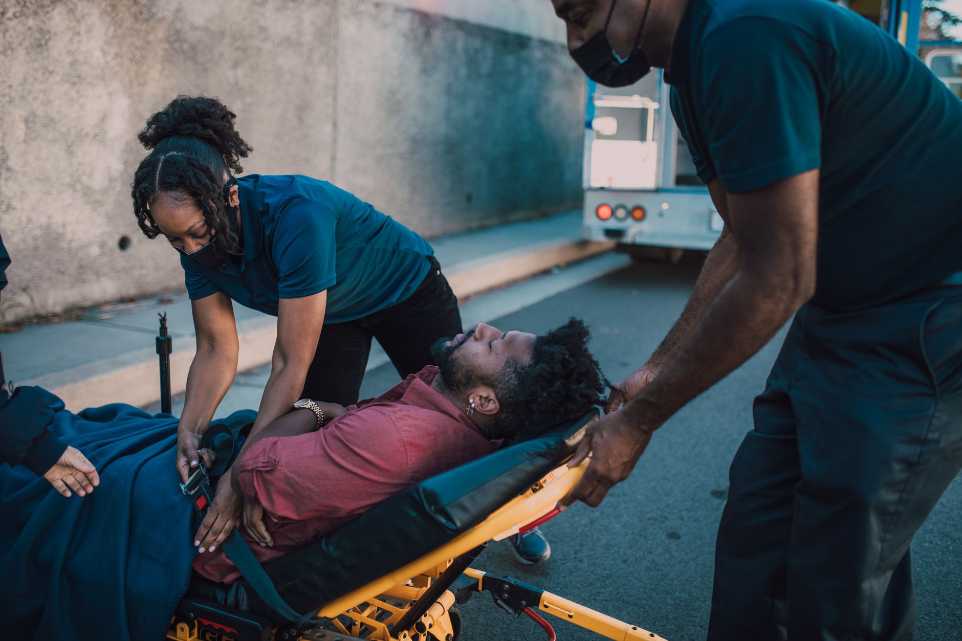 Paramedics attend to a patient on a stretcher outdoors during an emergency response.