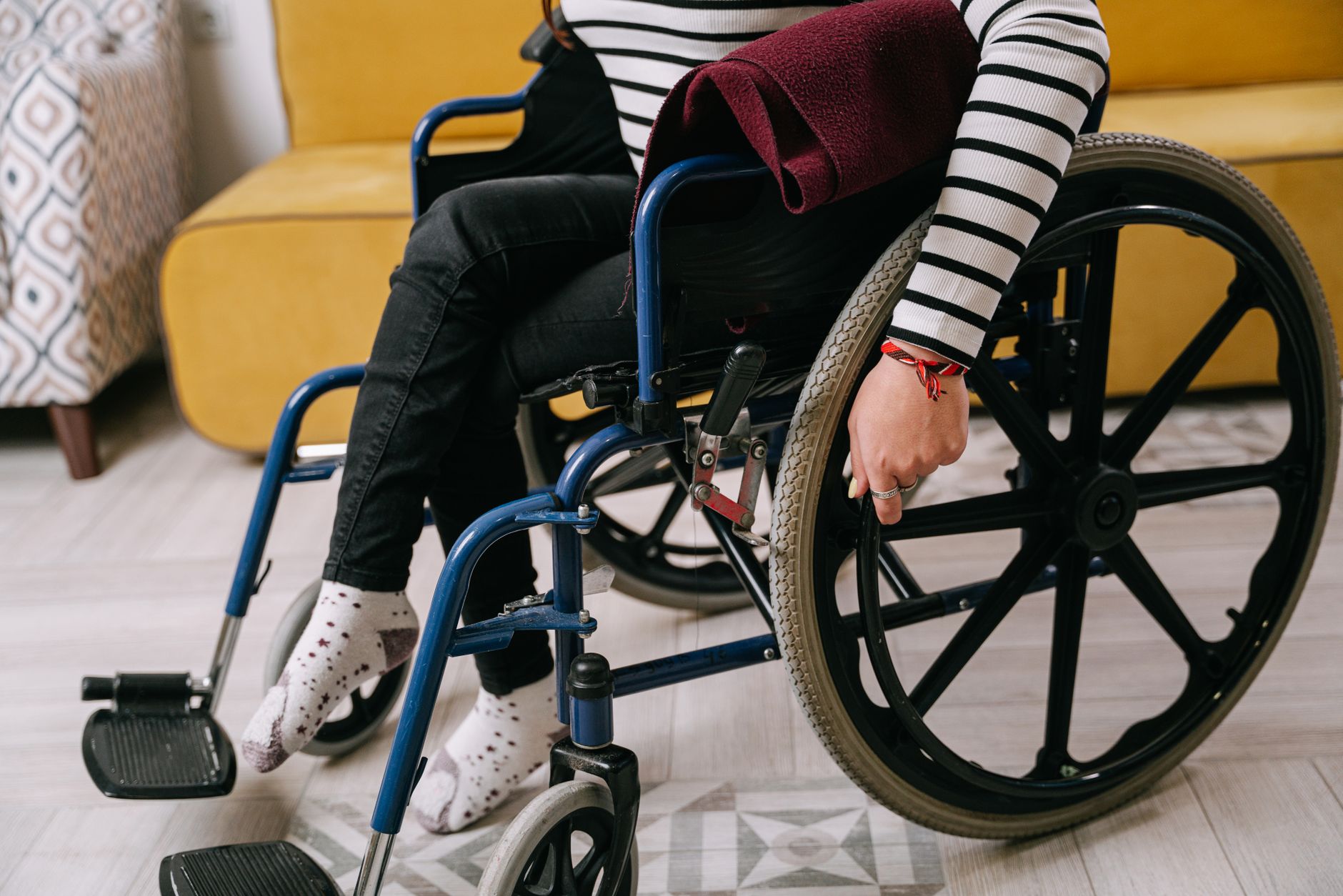 Person in a striped shirt seated in a wheelchair in a cozy indoor room.