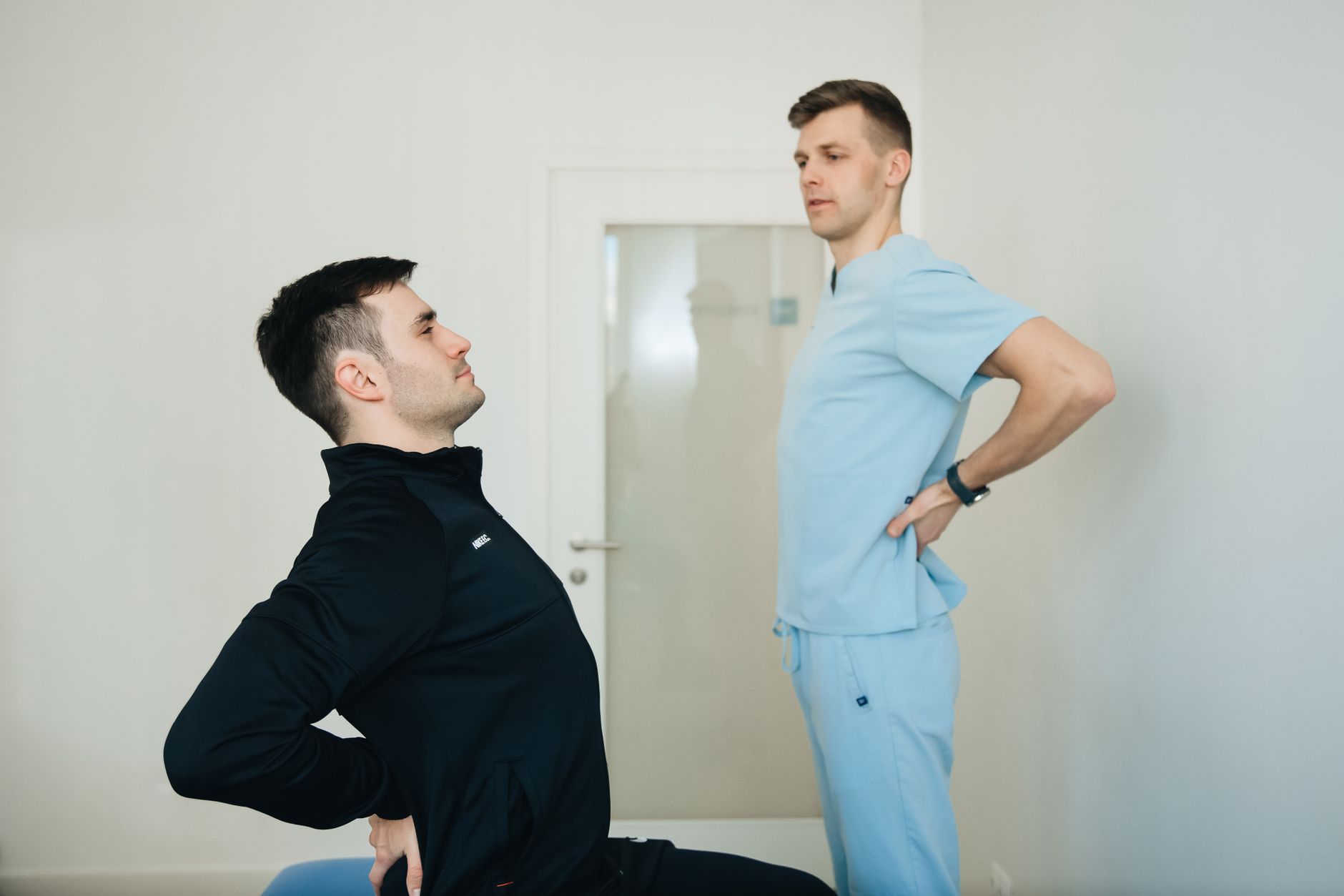 Physiotherapist guides a patient through back exercises in a clinic.