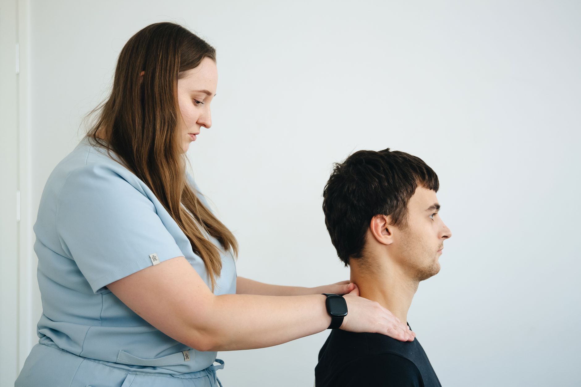 Physiotherapist treating a patient's neck pain in a clinic.