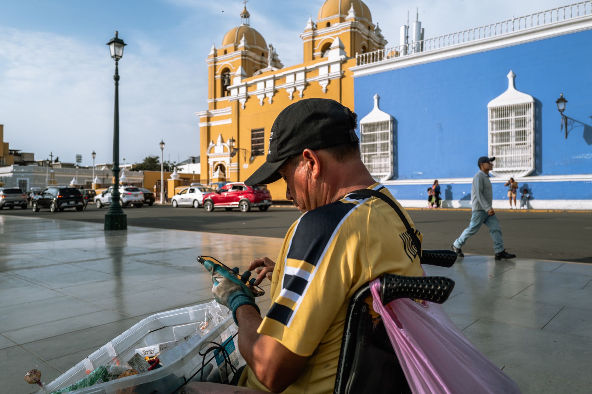 Vendedor ambulante trabajando frente a un edificio colonial de fachada azul y amarilla en Trujillo, Perú.