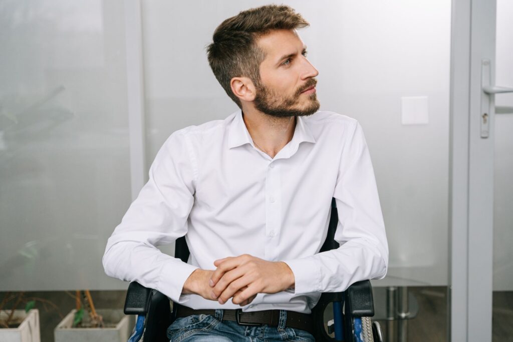Una persona en silla de ruedas mirando hacia adelante con determinación serena, lesión espinal catastrófica