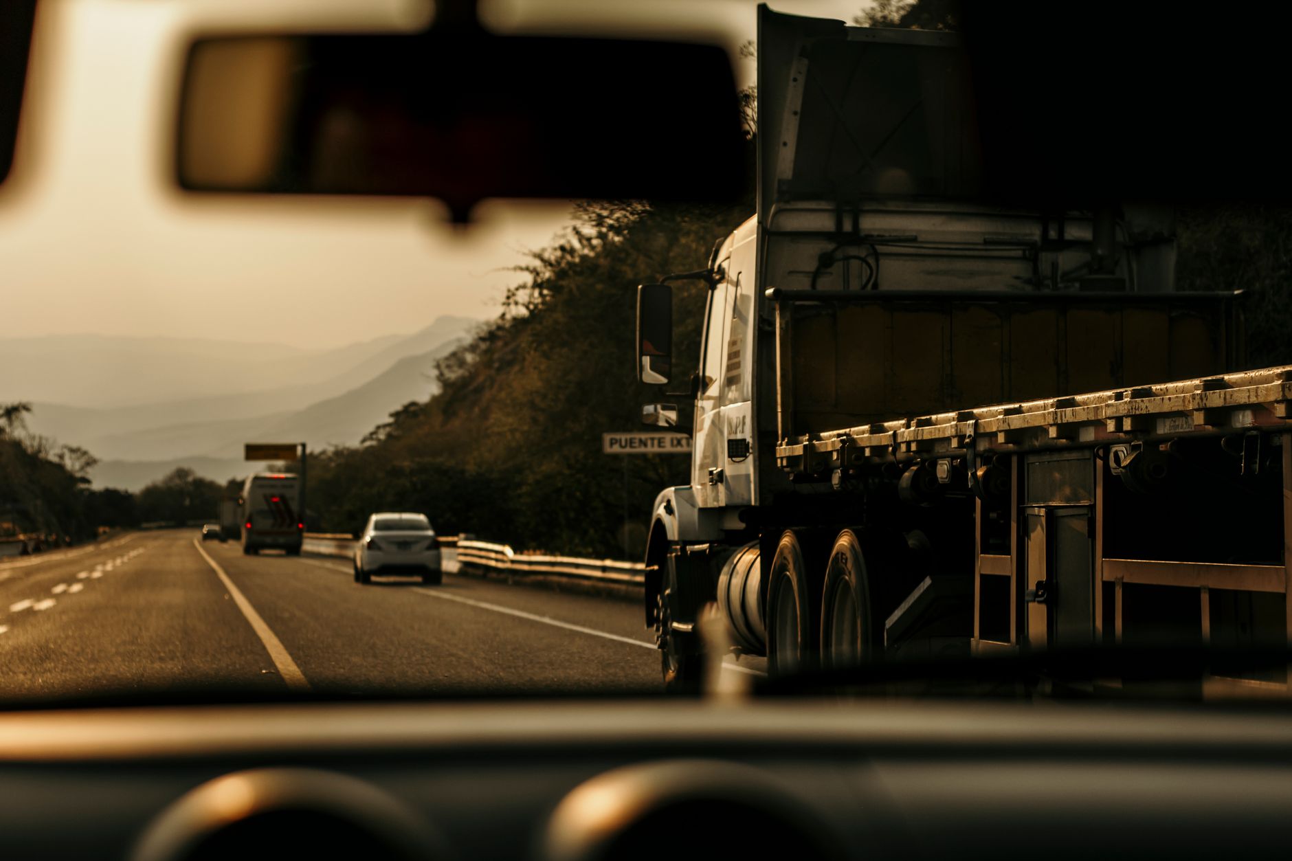 Cargo truck driving on a highway at sunset.