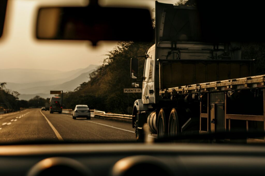Cargo truck driving on a scenic highway at sunset.