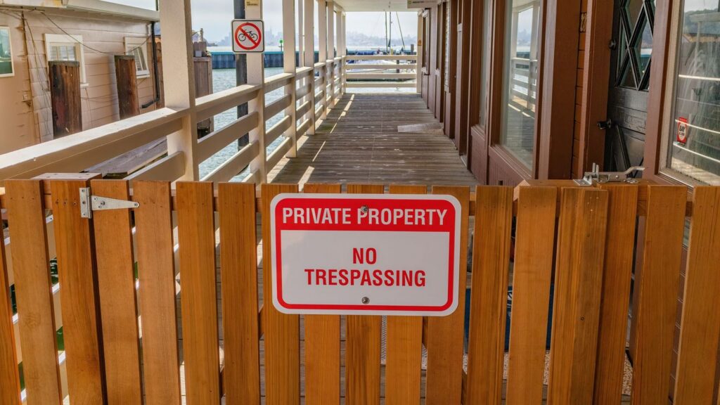 Cartel de propiedad privada y prohibido el paso en puerta de madera.