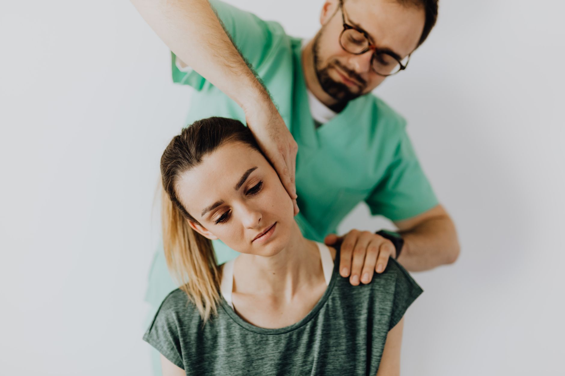 Massage therapist performs therapeutic neck treatment on a young female patient.