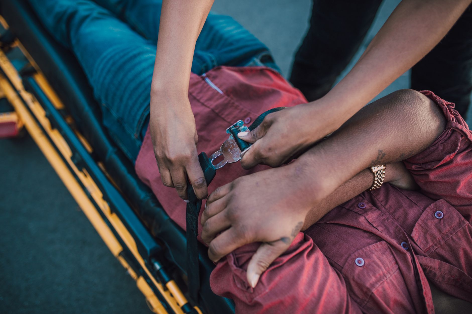 Paramedic securing an injured person onto a stretcher during emergency medical care.