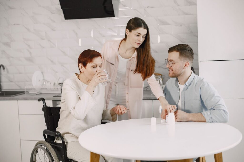 Elderly woman receiving support from family members in a kitchen.