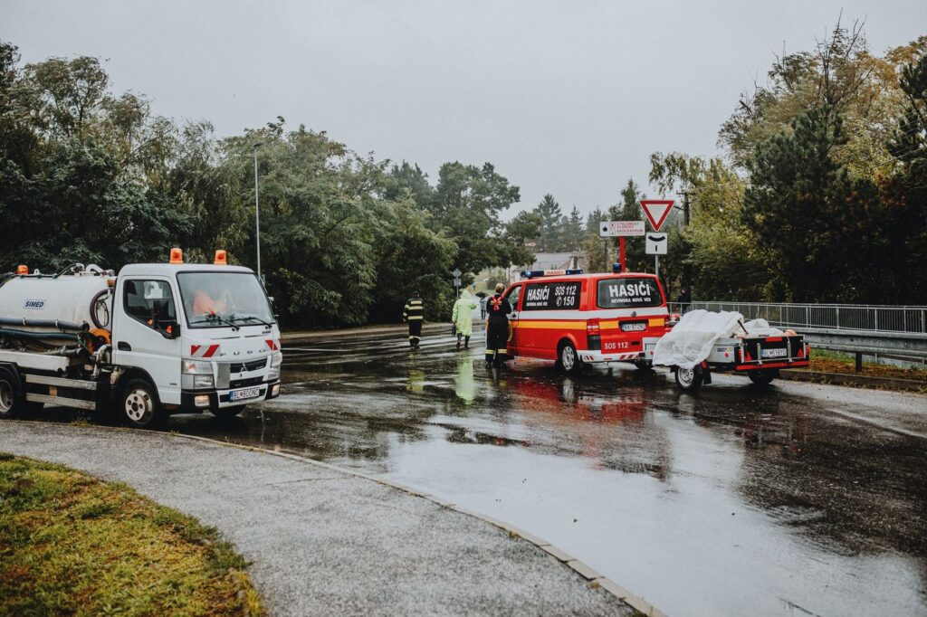 Emergency responders at accident scene on wet road with rescue vehicles.