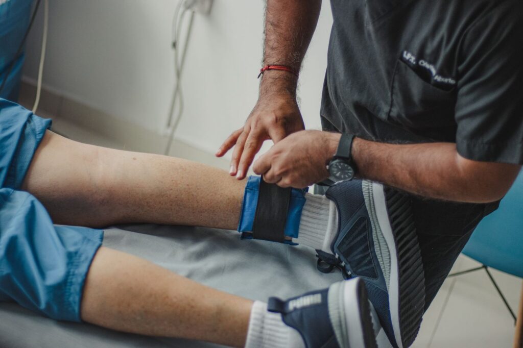 Fisioterapeuta ajusta una correa en la pierna de un paciente en clínica.