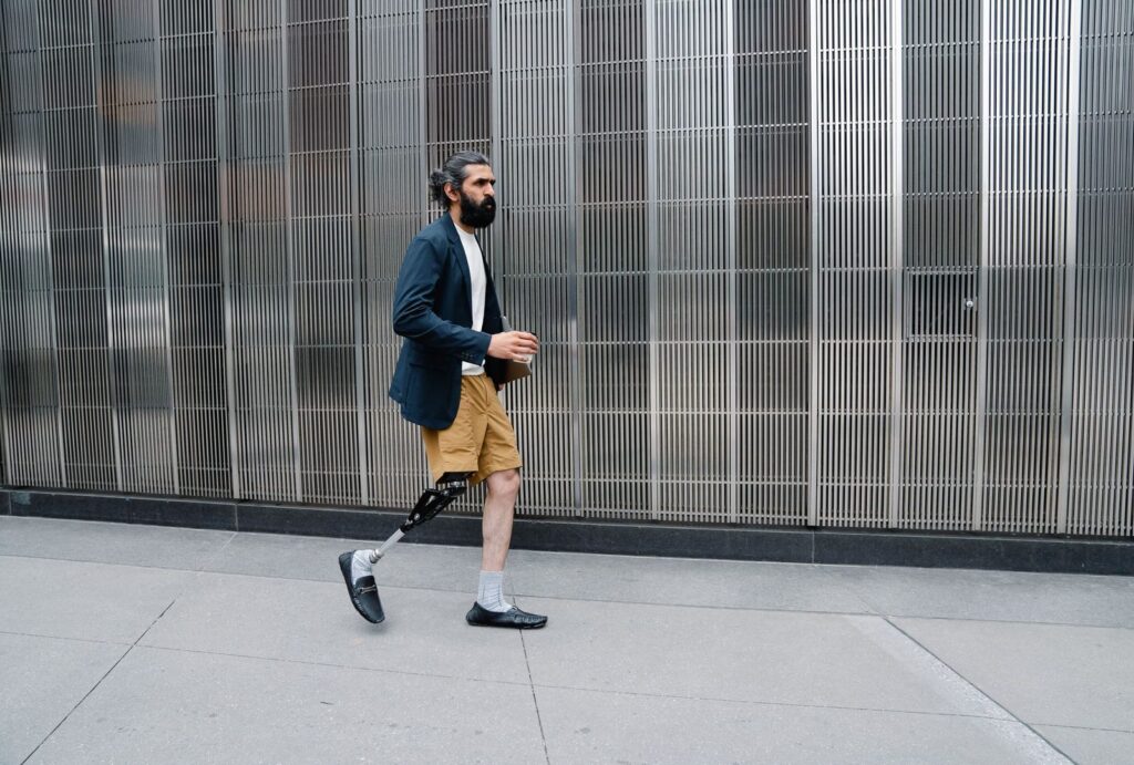 Hombre con prótesis de pierna caminando con confianza en entorno urbano.