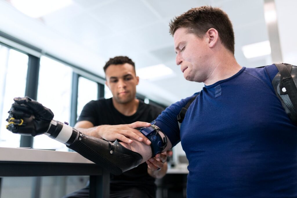 Ingeniero ajusta prótesis de brazo de alta tecnología a paciente en clínica moderna.