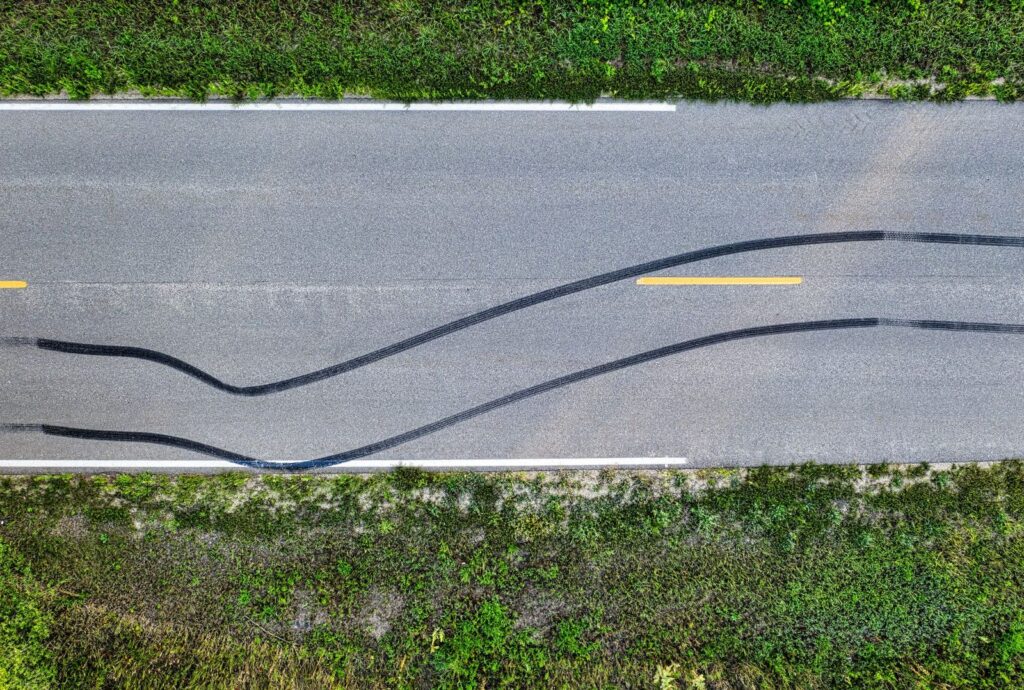 crash-reconstruction investigators documenting a motorcycle and its skid marks safely beside a closed roadway lane, featuring Hispanic and Latino people