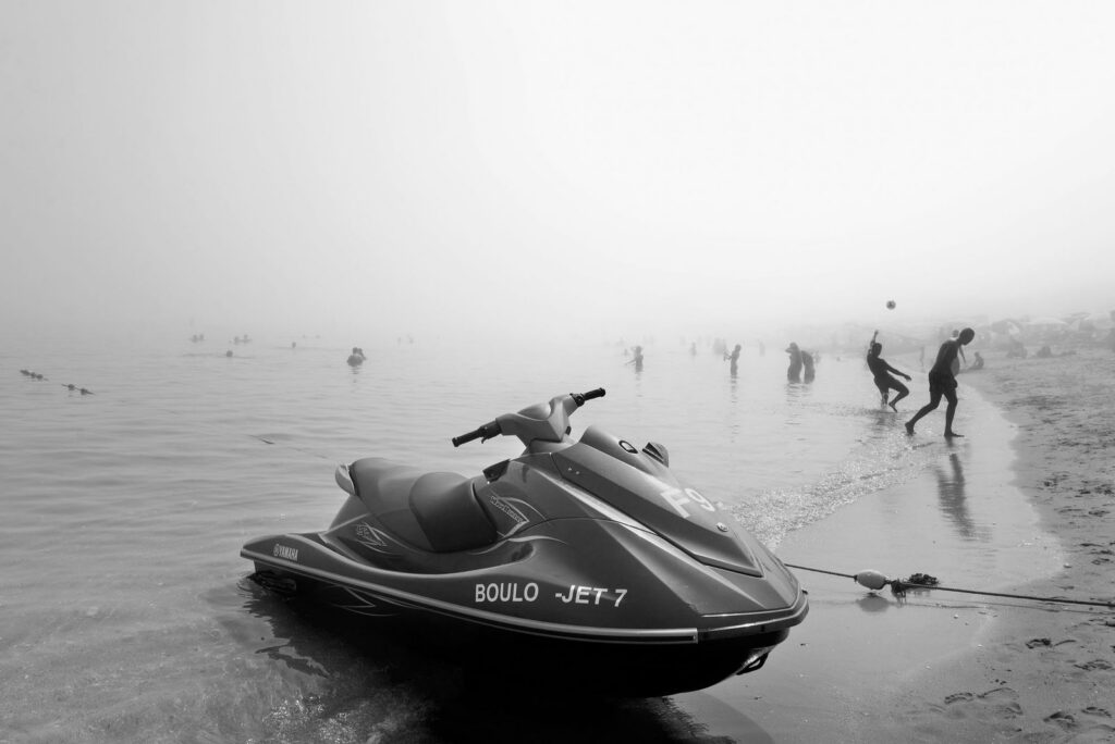 Jet ski en playa brumosa de Tétuan con bañistas disfrutando del día nublado.
