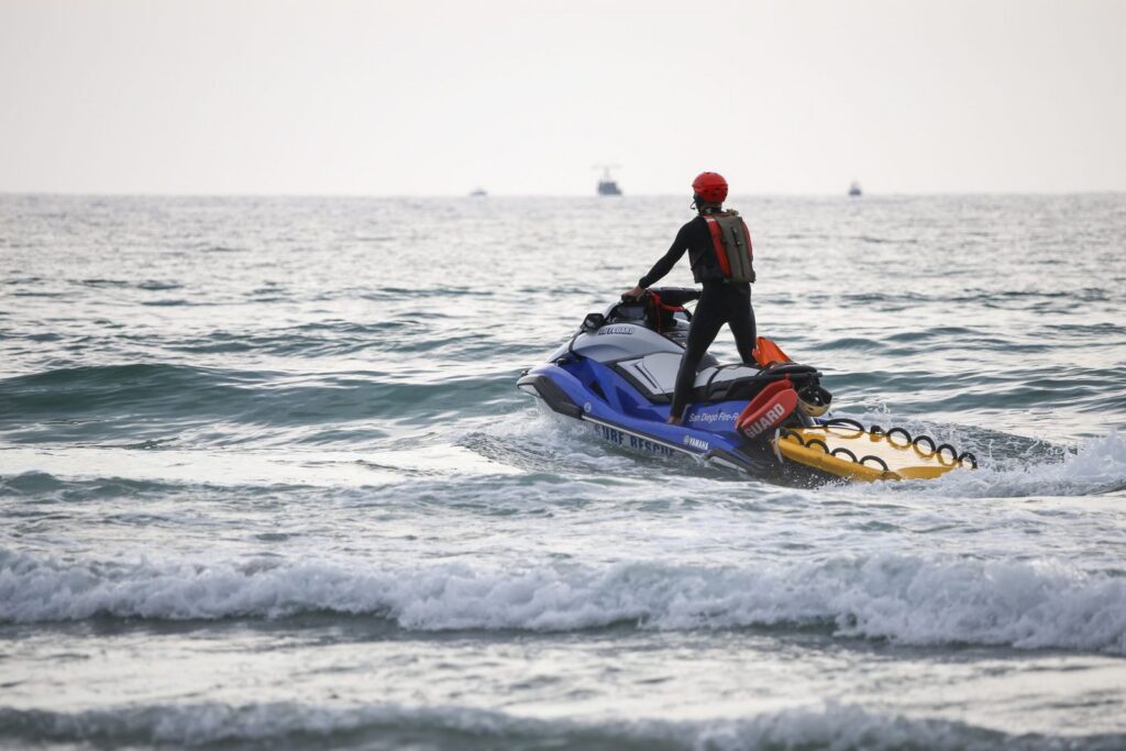 Lifeguard on jet ski patrolling ocean waters during daytime.