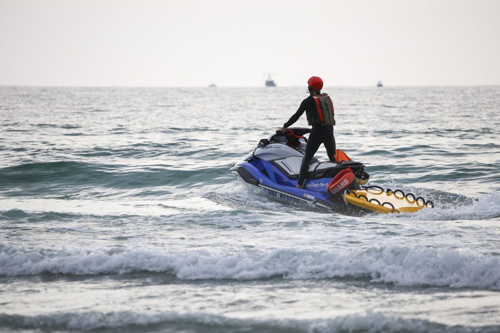 Lifeguard on jet ski patrolling ocean waters during daytime.