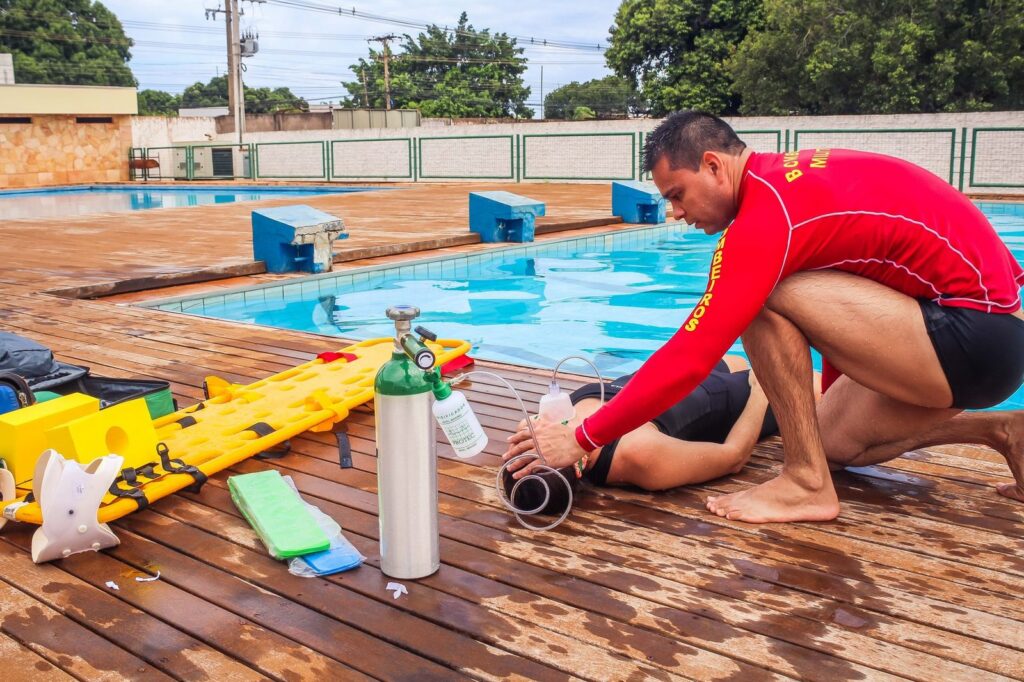 Lifeguard performing emergency resuscitation on an unconscious swimmer at poolside.
