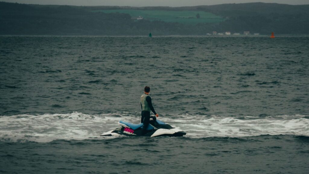 Man riding a jet ski across ocean water on a cloudy day.
