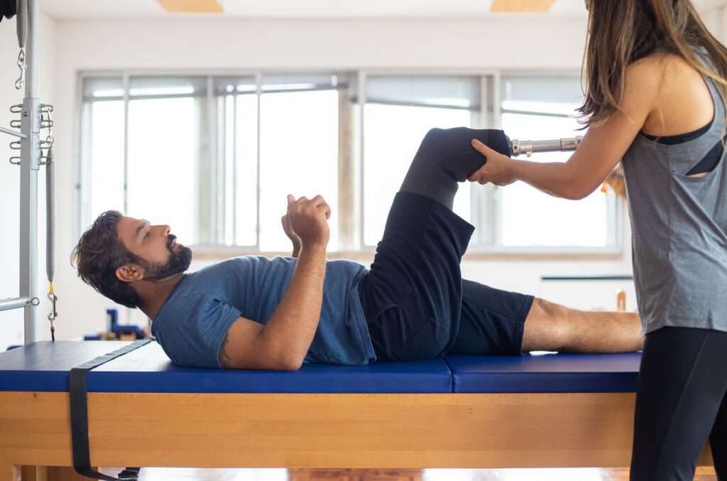 Man with prosthetic leg working with a therapist during a rehabilitation session.