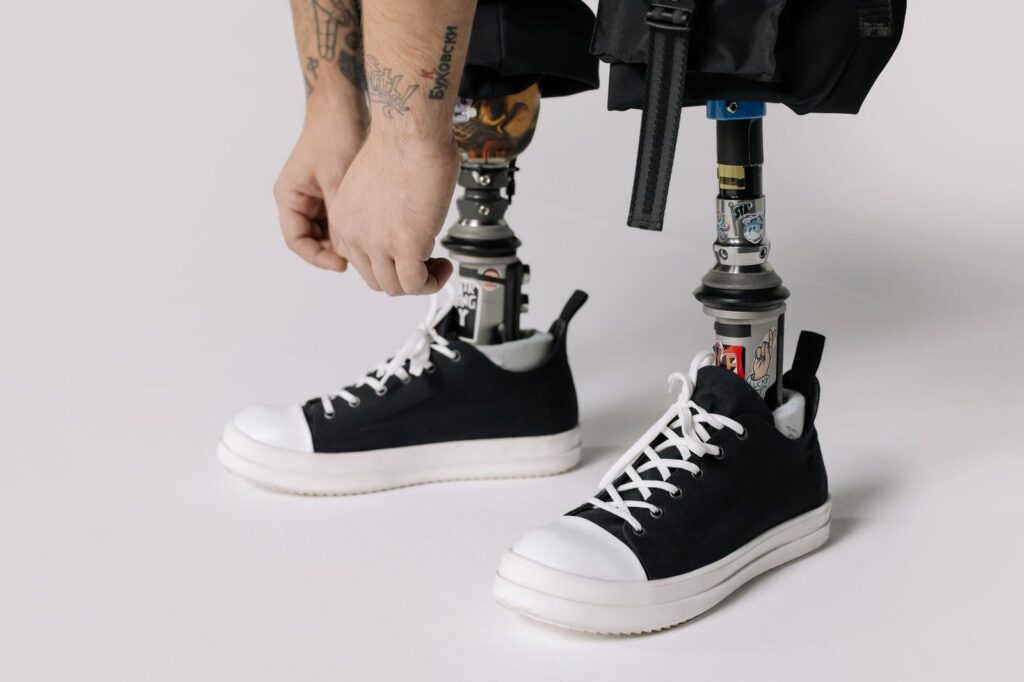 Man with prosthetic legs tying shoelaces on sneakers.