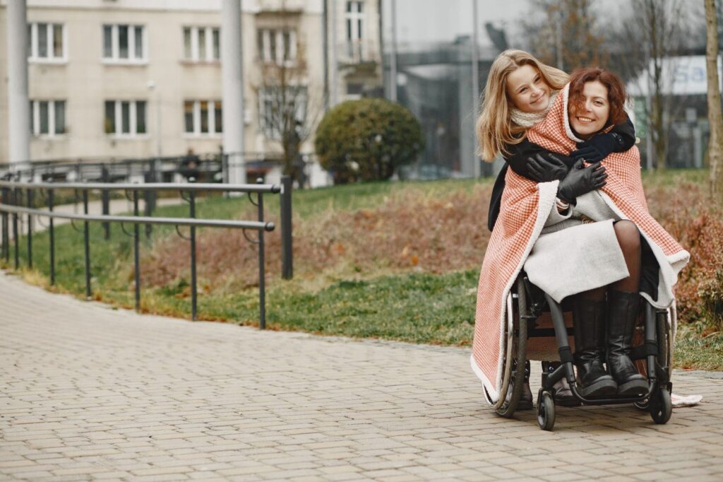 Mother and daughter hugging in a park, representing family support and mobility.