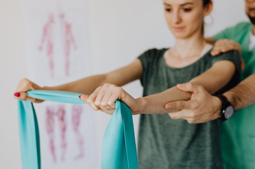 Orthopedist applying elastic tape to patient's arm in medical office.