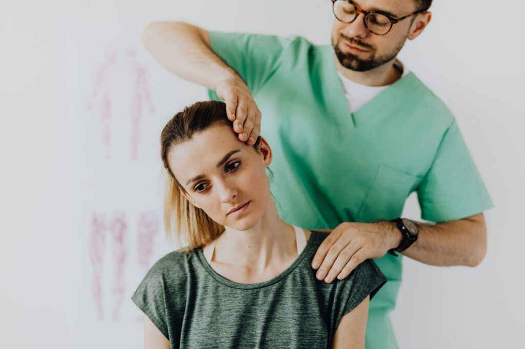 Osteopath examining patient's neck in hospital setting.