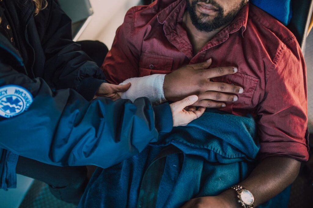 Paramedic treating patient with bandaged arm in emergency setting.