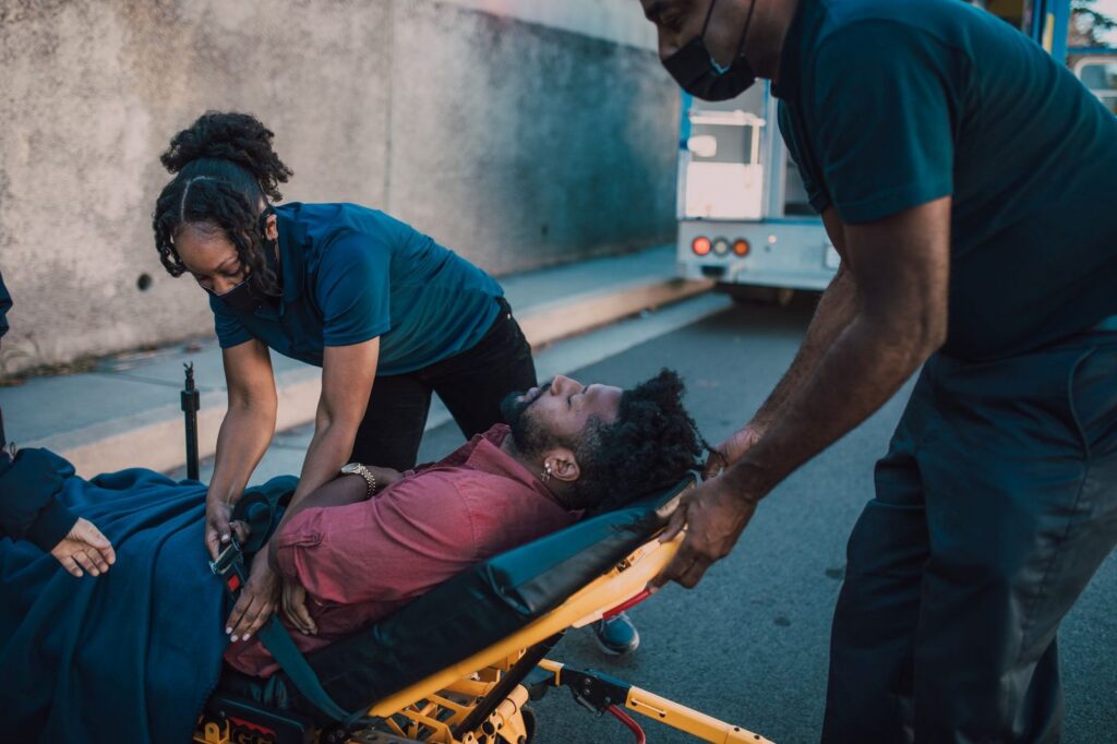 Paramedics providing emergency care to an injured patient outdoors.