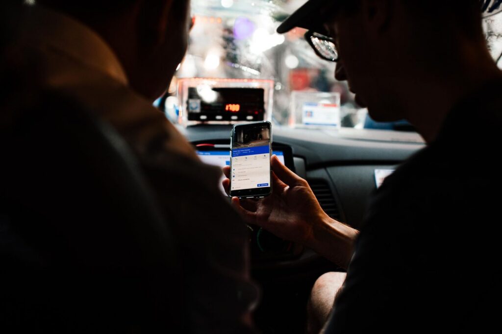 Passengers checking directions on smartphone inside car at night.