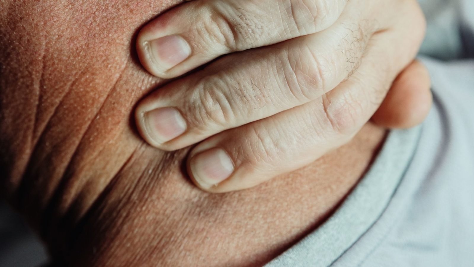 Person holding neck in pain or discomfort.