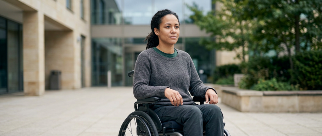 Person using a wheelchair looking forward with quiet resolve after a catastrophic spinal injury.