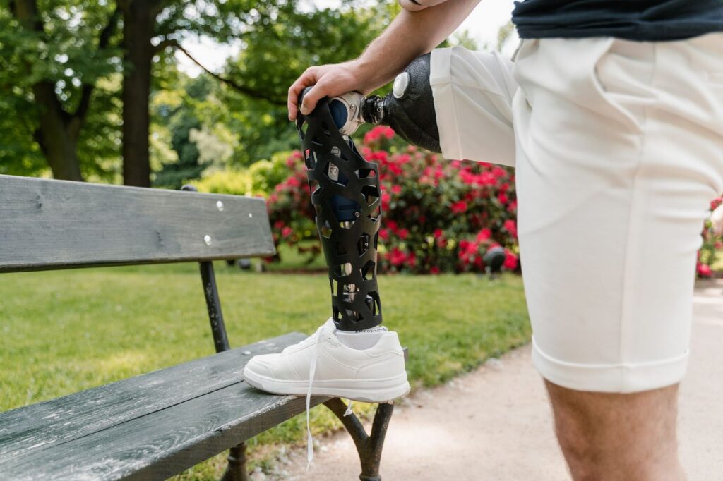 Person with prosthetic leg resting on park bench in garden.