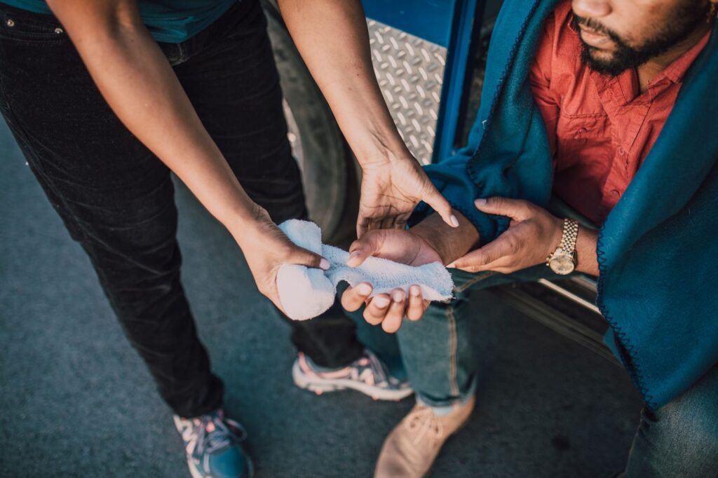 Persona aplicando gasa en mano lesionada como primeros auxilios.