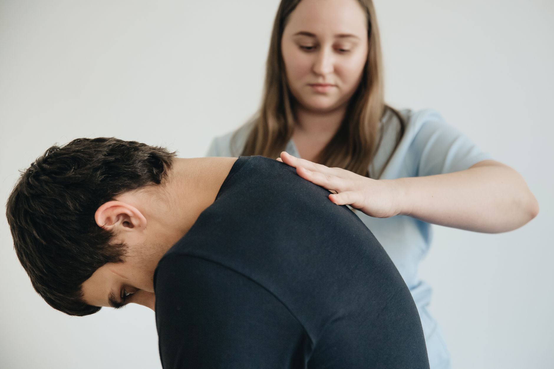 Physiotherapist assisting a patient experiencing lower back pain in a clinic.