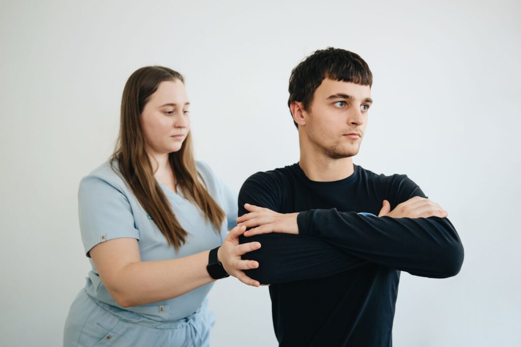 Physiotherapist assists a patient with arm exercises in a clinical rehabilitation setting.