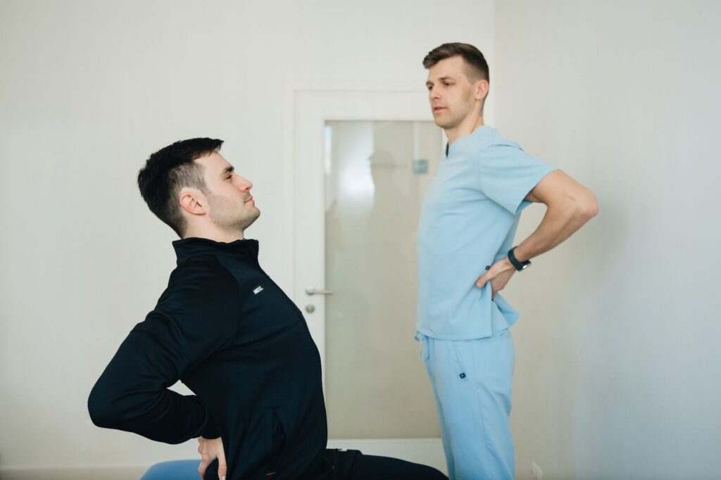 Physiotherapist guiding patient through back exercises in clinic.