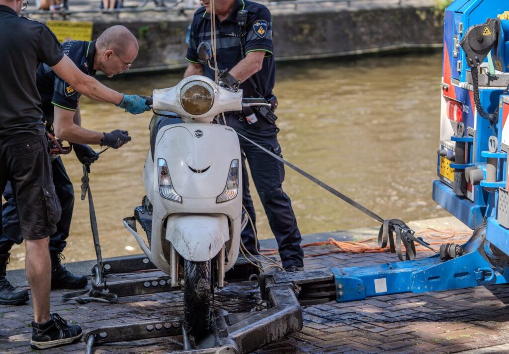 Policías retiran una motocicleta de un canal con equipo de remolque.