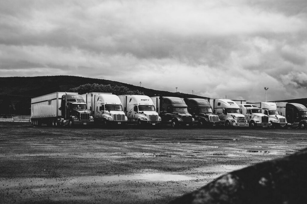 Semi trucks parked in rain, black and white photograph.