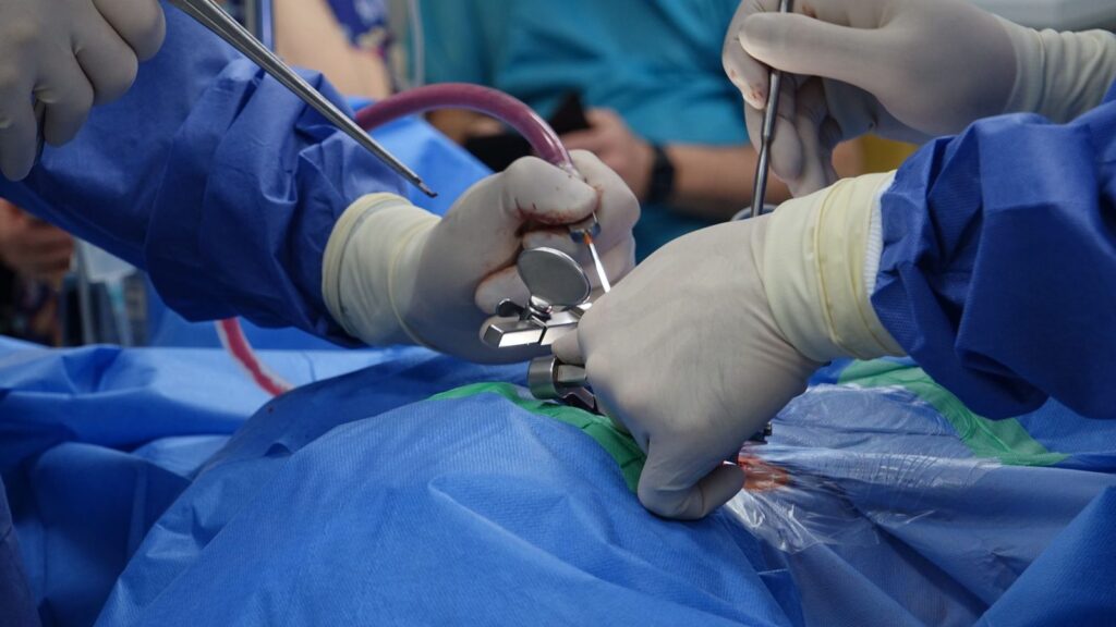 Surgeons performing spinal surgery in a sterile operating room with precision instruments.