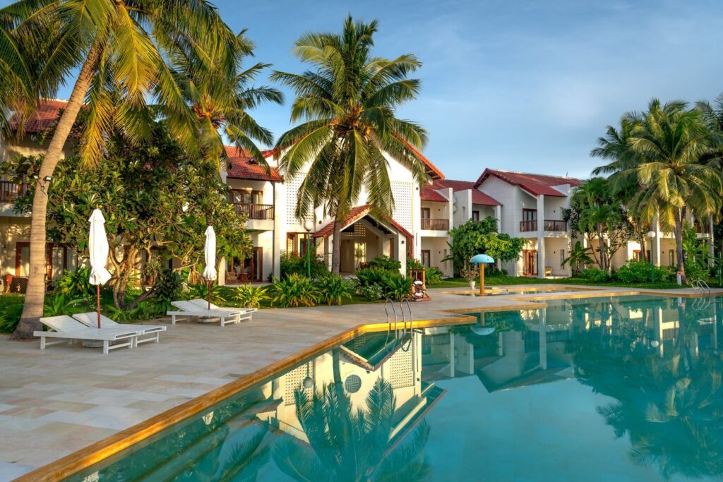 Tropical resort pool with palm trees and poolside lounge area.