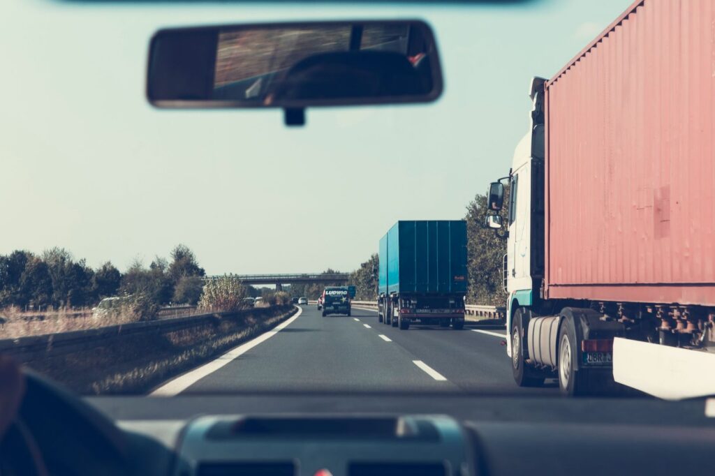 Trucks on a German highway viewed through a rearview mirror.